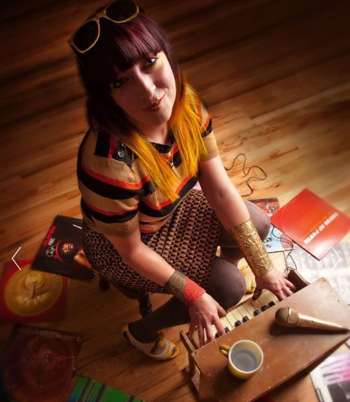 A woman is kneeling on the floor playing a keyboard