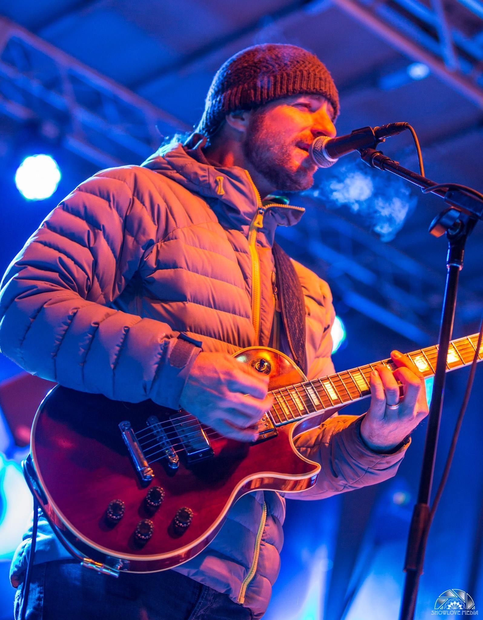 A man is playing a guitar and singing into a microphone.
