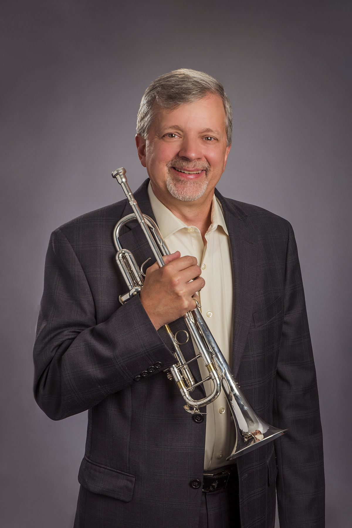 A man in a suit is holding a trumpet in his hand.