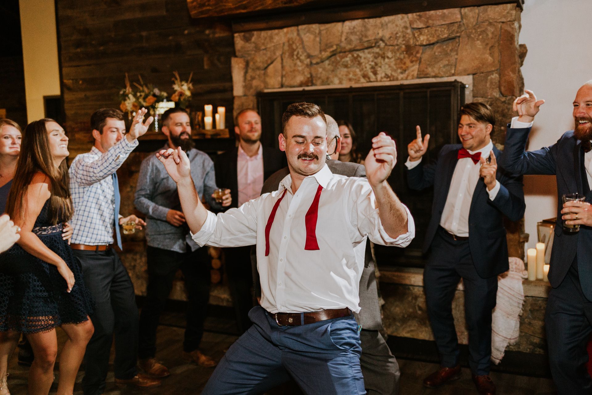 A man is dancing in front of a group of people at a wedding reception.