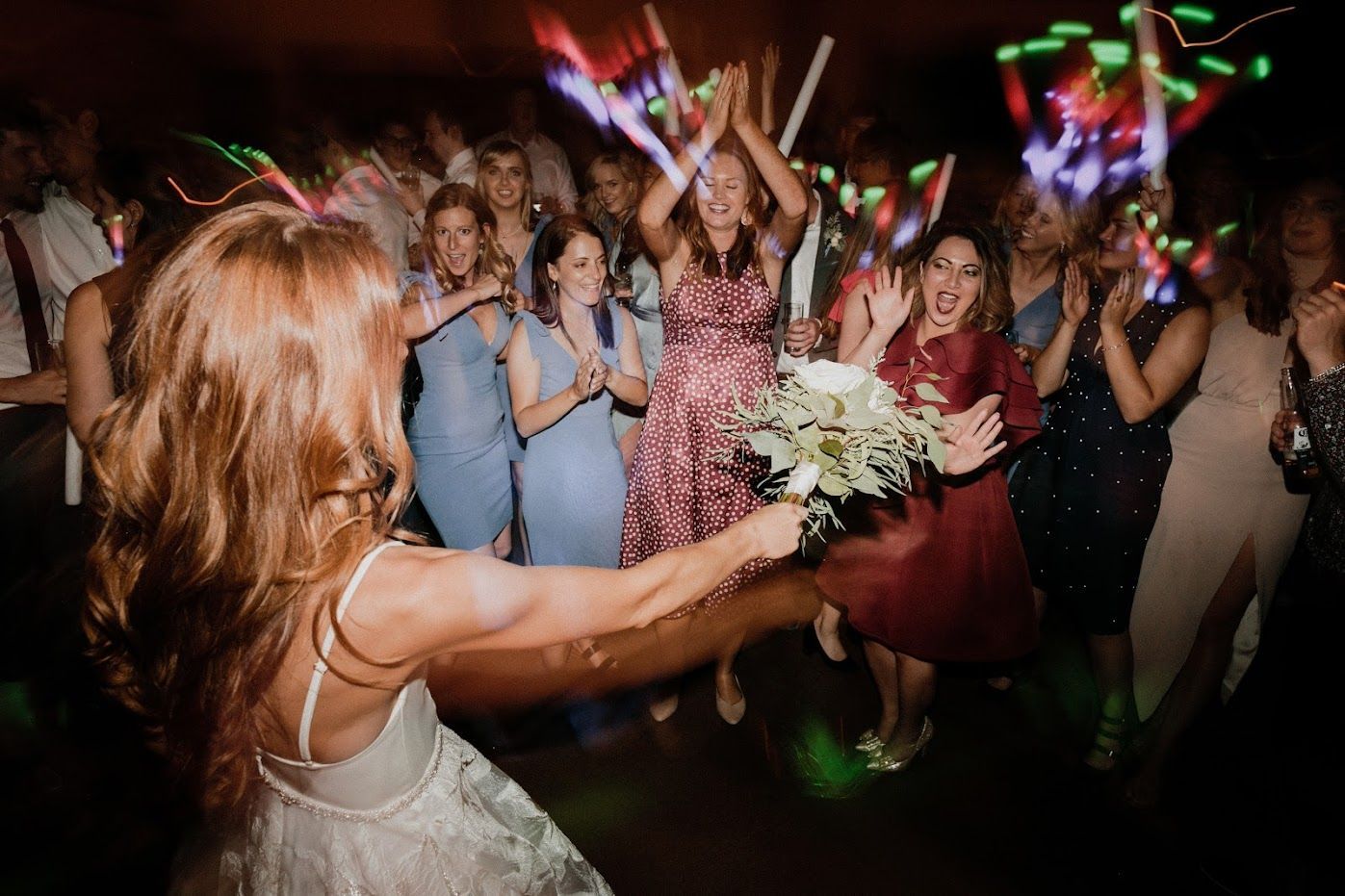A bride is throwing a bouquet of flowers to her bridesmaids at a wedding reception.