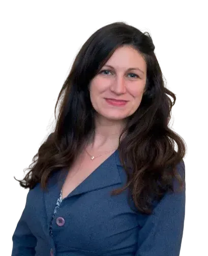 Woman with long dark hair smiles, wearing a blue blazer over a patterned top.