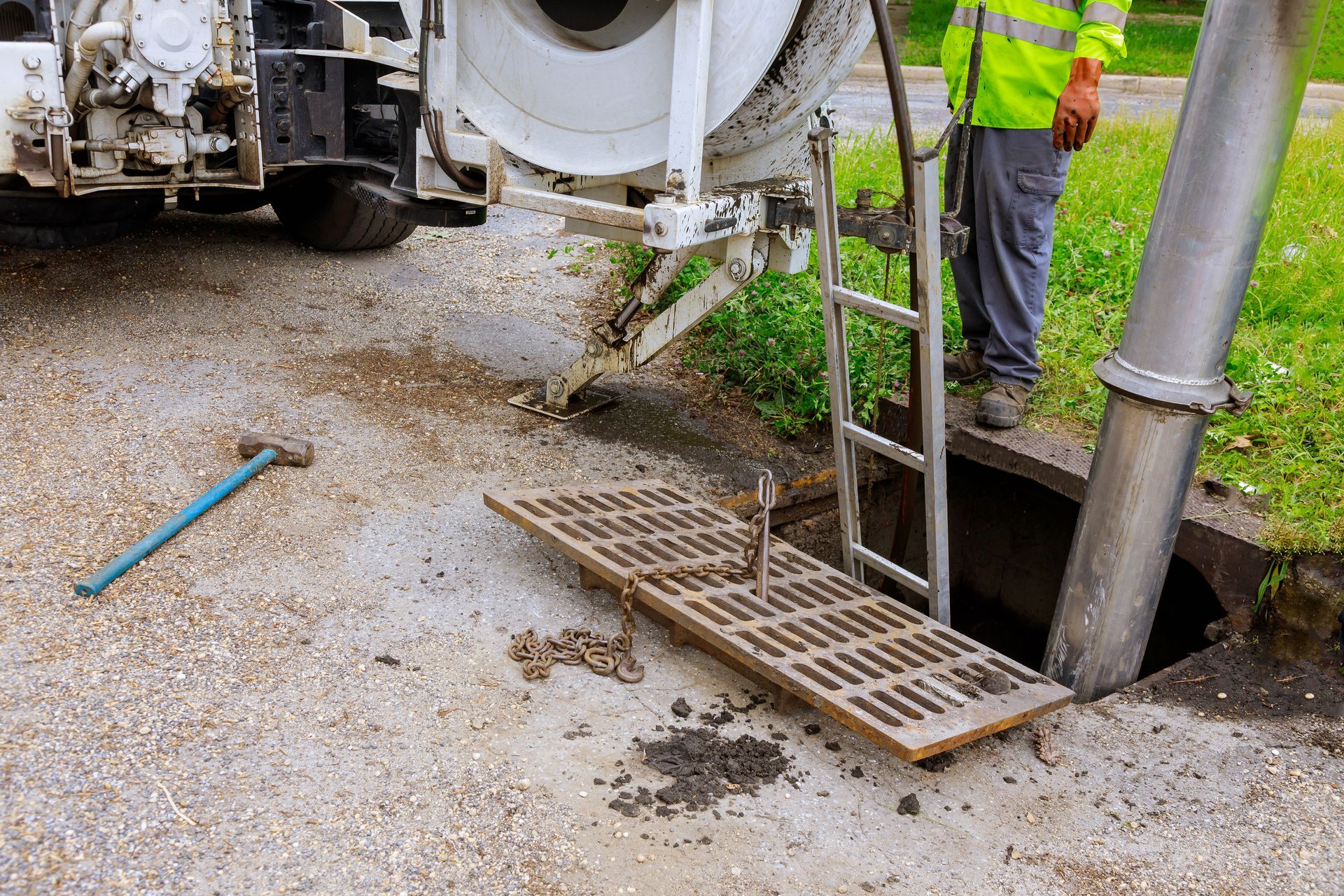 A man is standing next to a vacuum truck cleaning a drain.