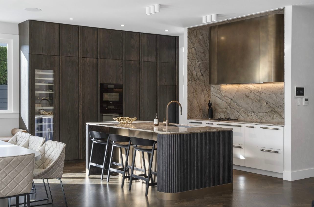 Modern kitchen with dark wood cabinets, marble island, and built-in appliances