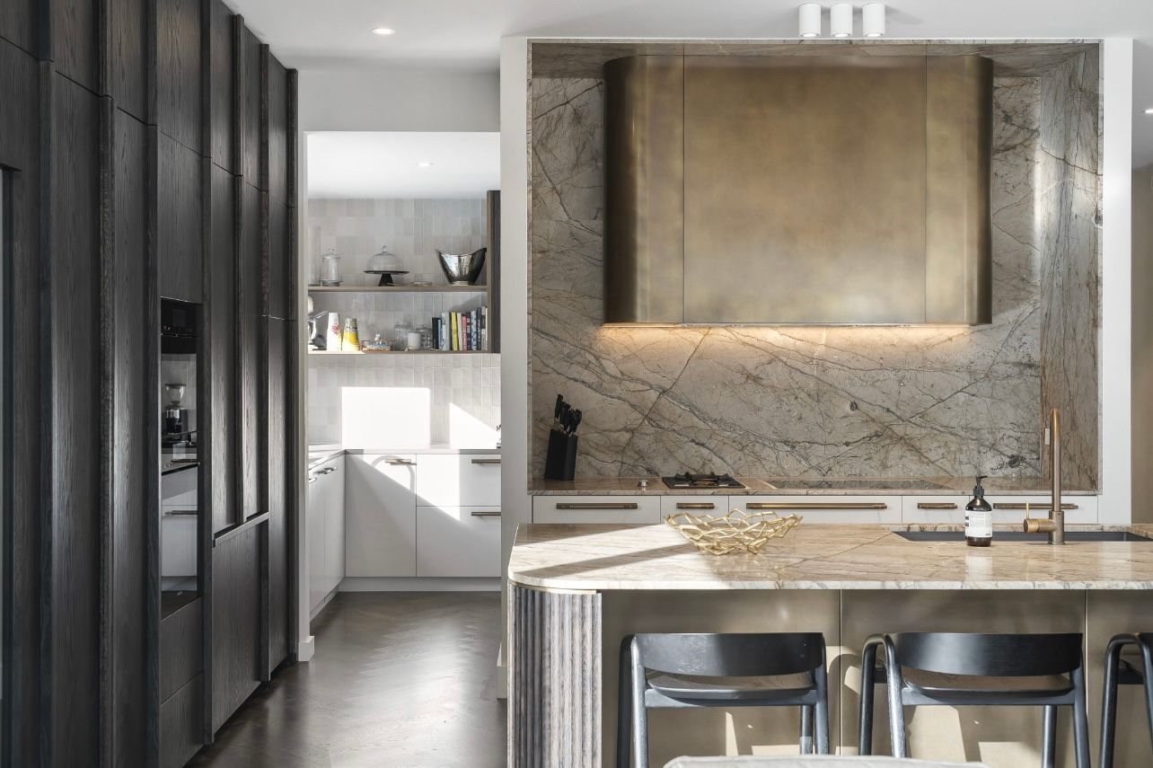 Modern kitchen with gray cabinetry, white island, and metallic backsplash in a bright interior