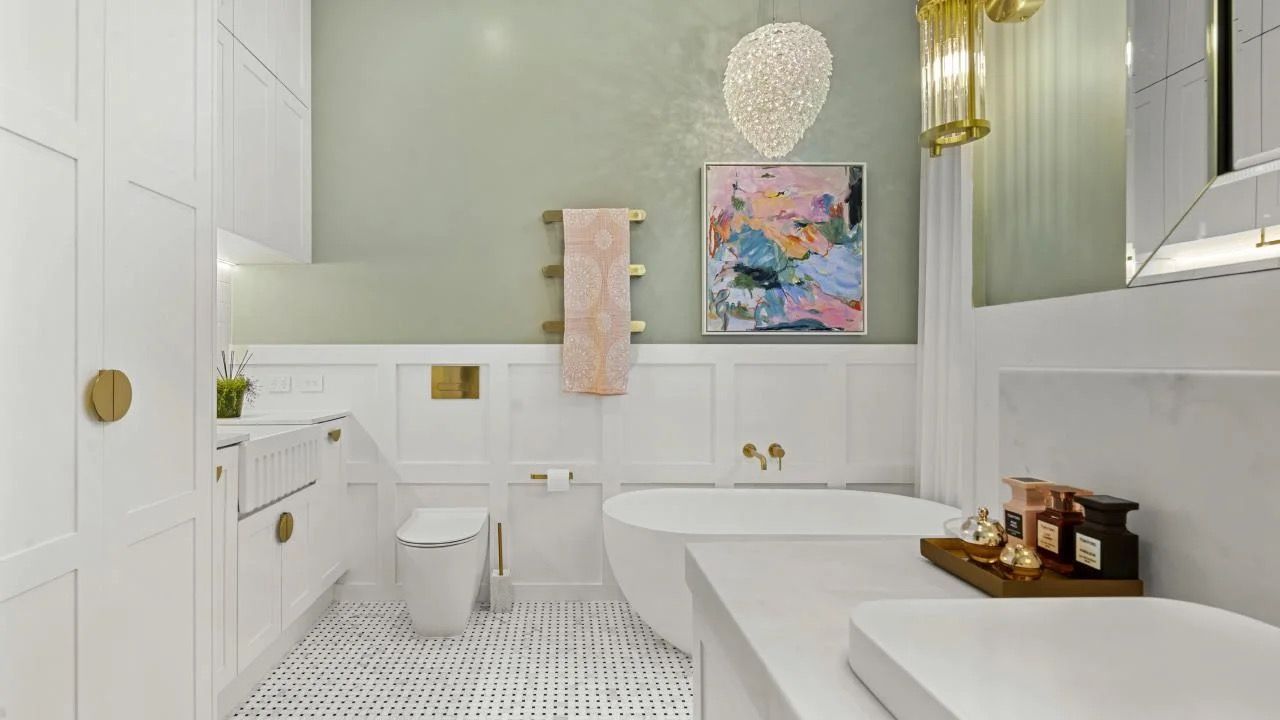 Bright white bathroom with a freestanding tub, toilet, sink, and colorful wall art