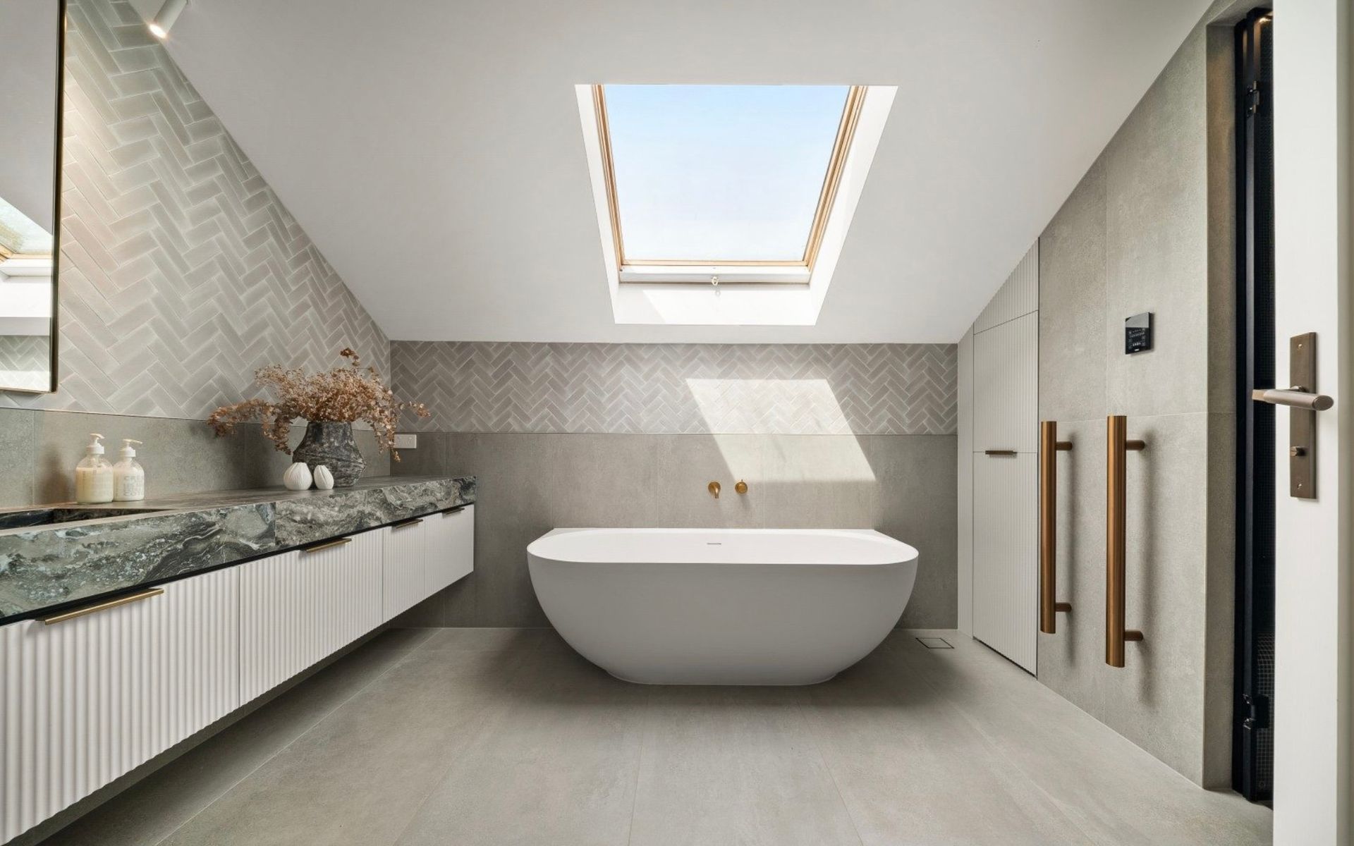 Modern bathroom with floating vanity, large mirror, skylight, and freestanding tub