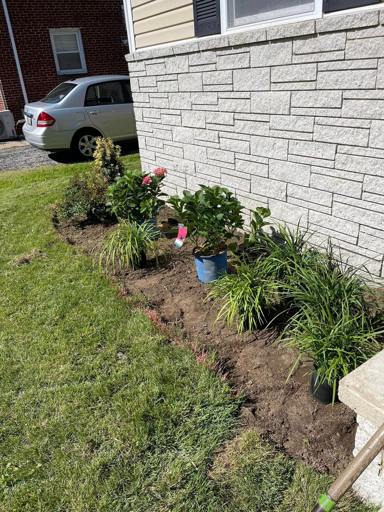 A car is parked in front of a brick wall next to a garden.