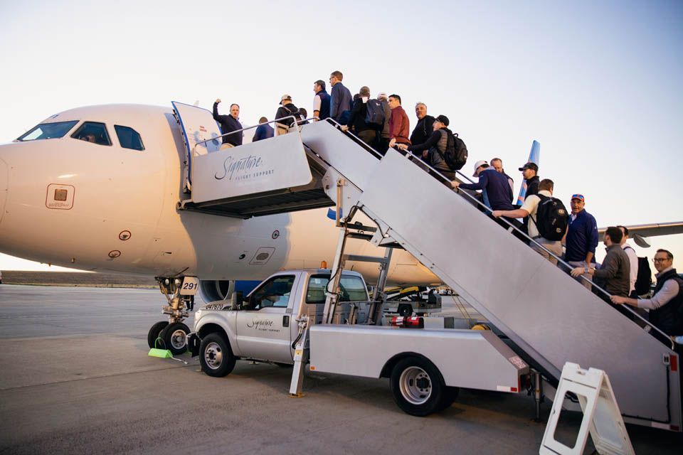 Long line of golfers on stairs boarding airplane to Las Vegas for golf tournament.