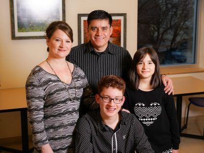 A T1D family of four posing for a picture together in a room.
