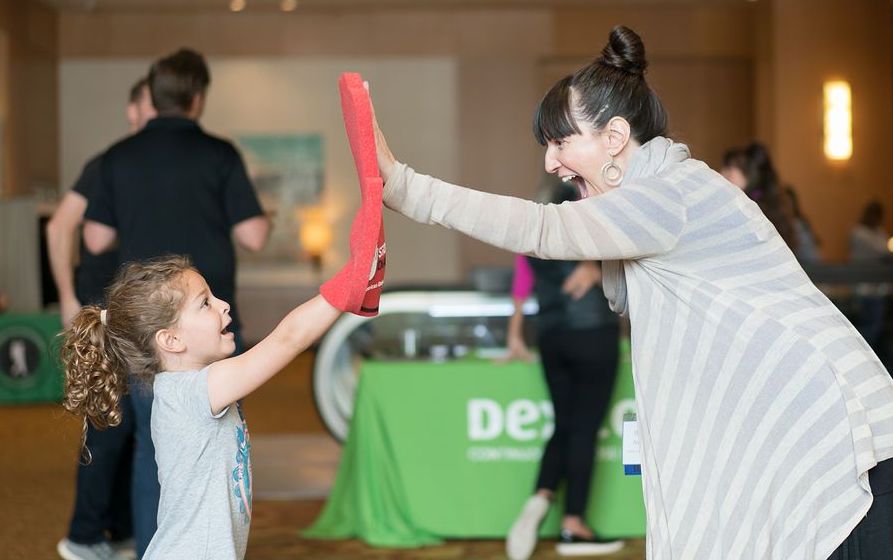 Young girl wearing a foam finger and giving a woman a high five at EPIC conference.