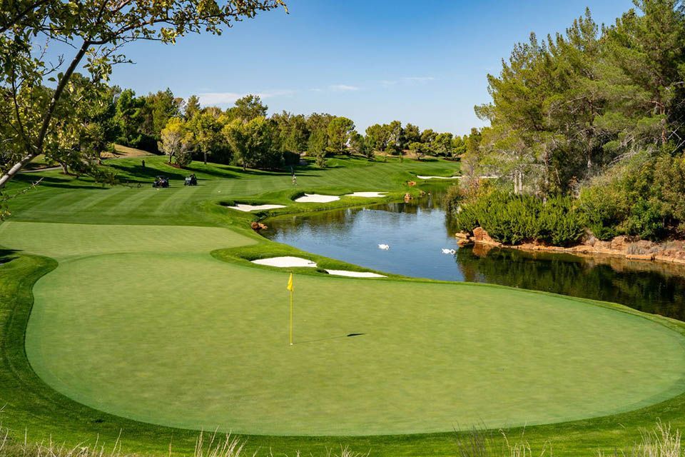 A golf course with a pond in the middle of it.