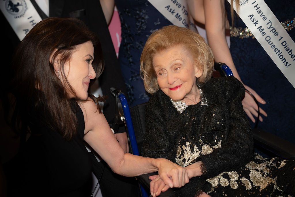 CDF Executive Director and her mother, founder Barbara Davis, holding hands and smiling at one another.