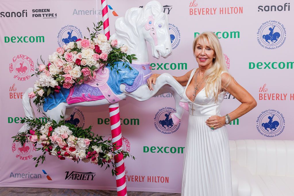 CDF supporter and event attendee Linda Thompson posing with carousel horse on red carpet.