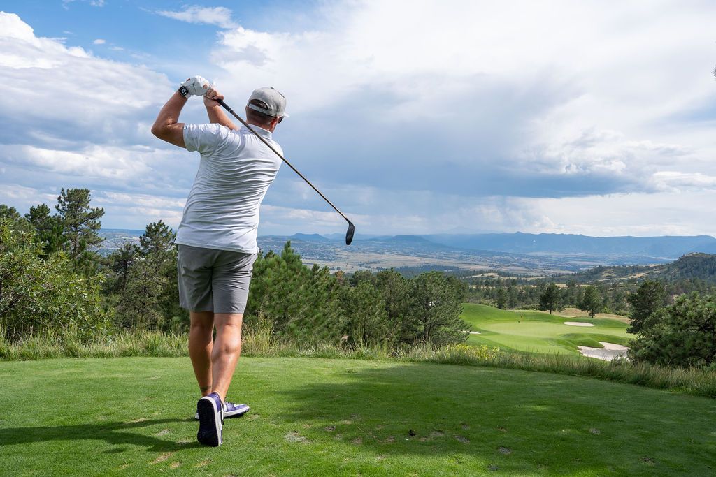 Male golfer in his back swing on the tee box, watching where his ball went.
