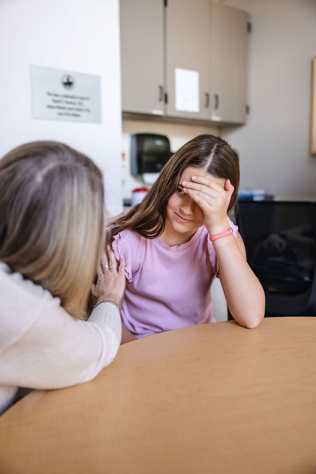 Teen girl with head in hand being comforted by social worker. 