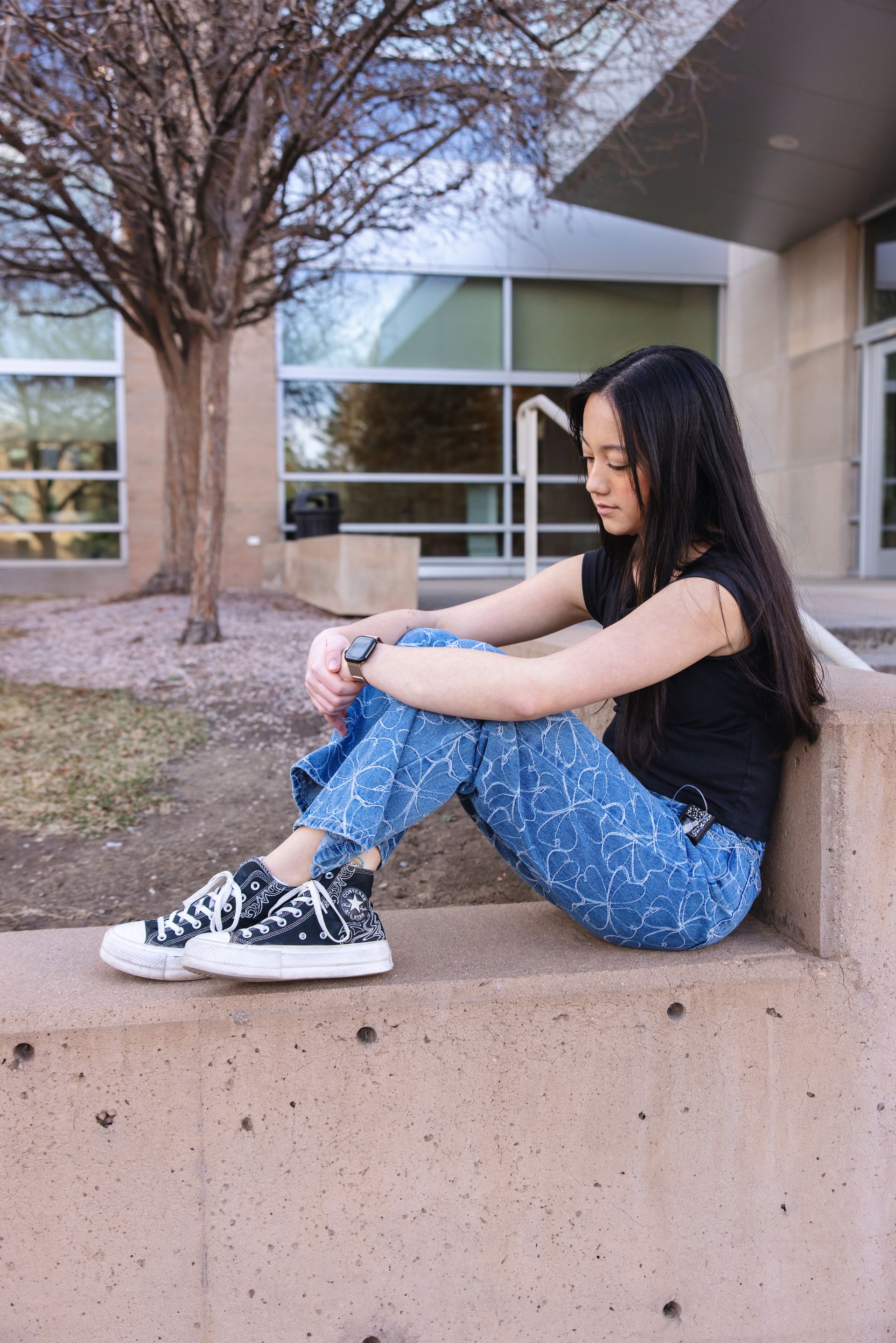 Teenage girl with insulin pump sitting with her knees up and looking unwell.