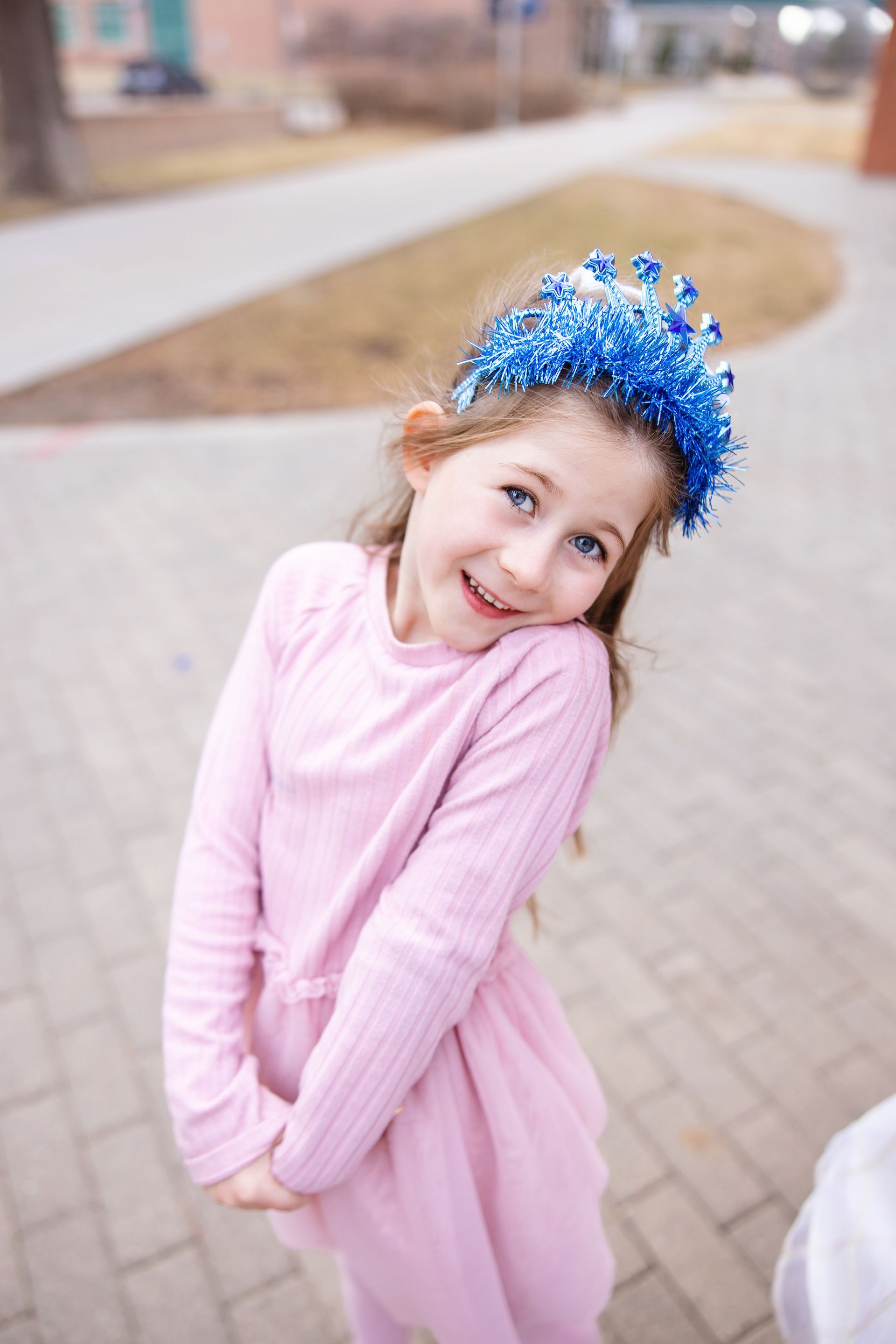 Smiling young girl in pink dress and blue headband.
