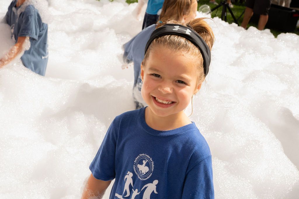 Little girl smiling while playing in finish line foam party at race