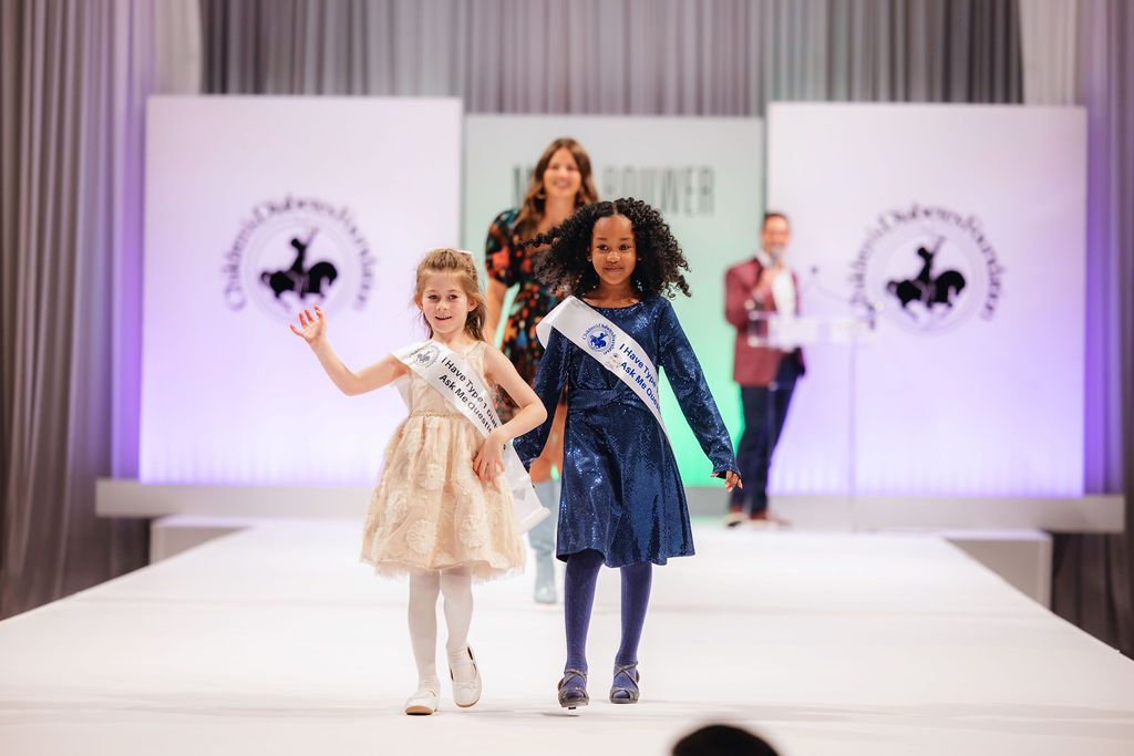 Two children walking in the Brass Ring Luncheon and Fashion Show. 