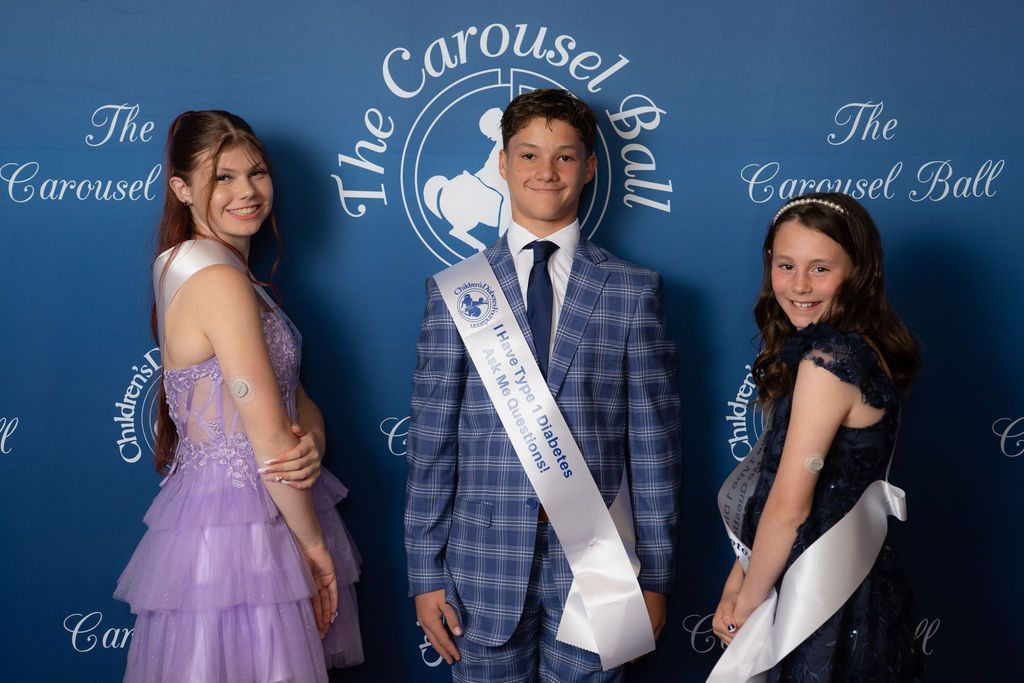 Three CDF advocates, two girls and a boy, posing on the red carpet with sashes that say ask me about type 1