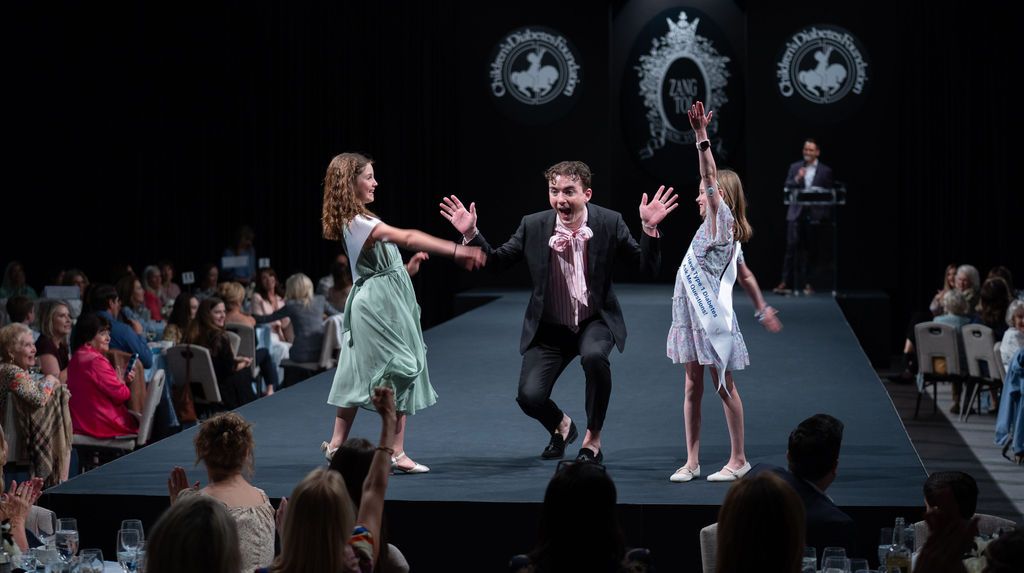 two young t1d advocates girls on runway giving a male clinician a high five on the runway