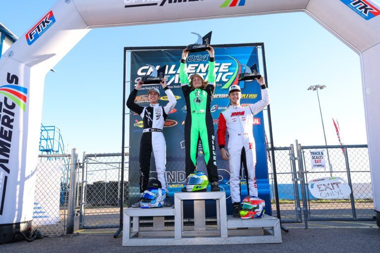 Three people standing on a podium with a banner that says challenge america