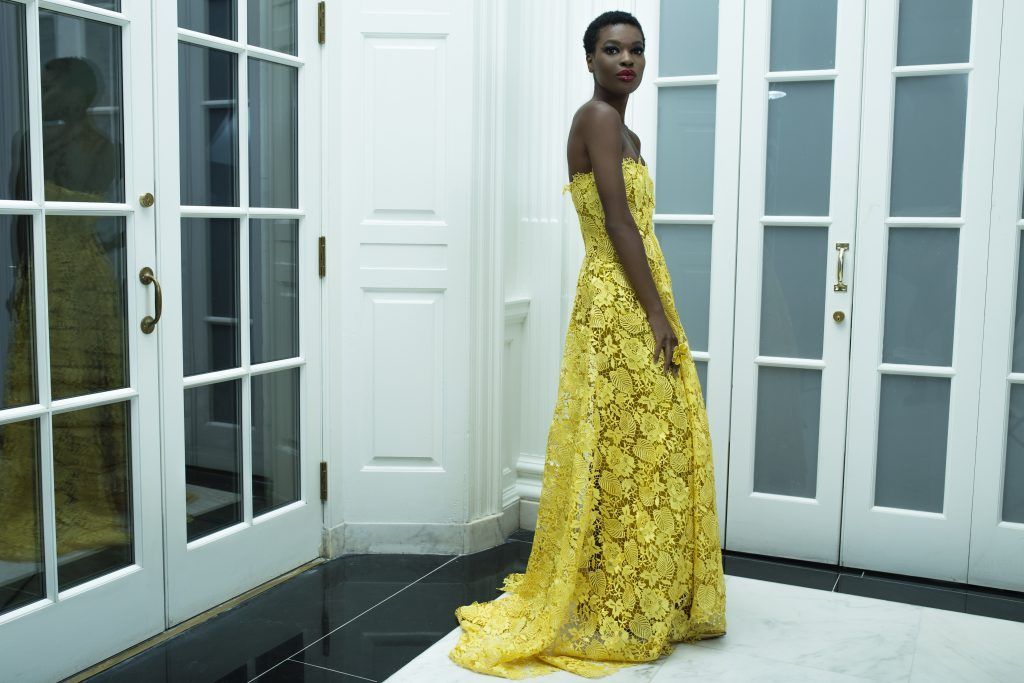 A woman in a yellow dress is standing in a room.