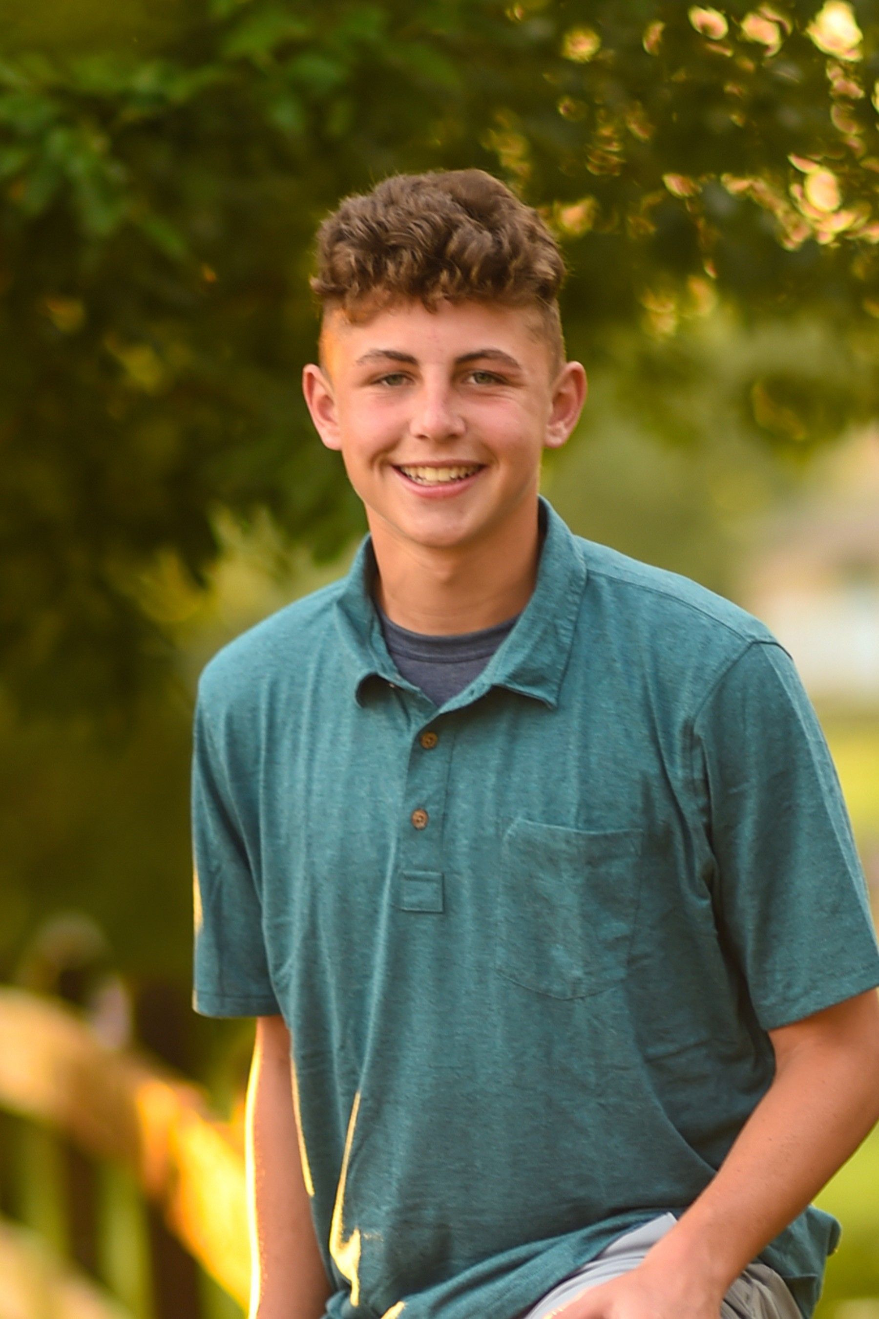 Cade as a thriving teenager, outside in green shirt and smiling