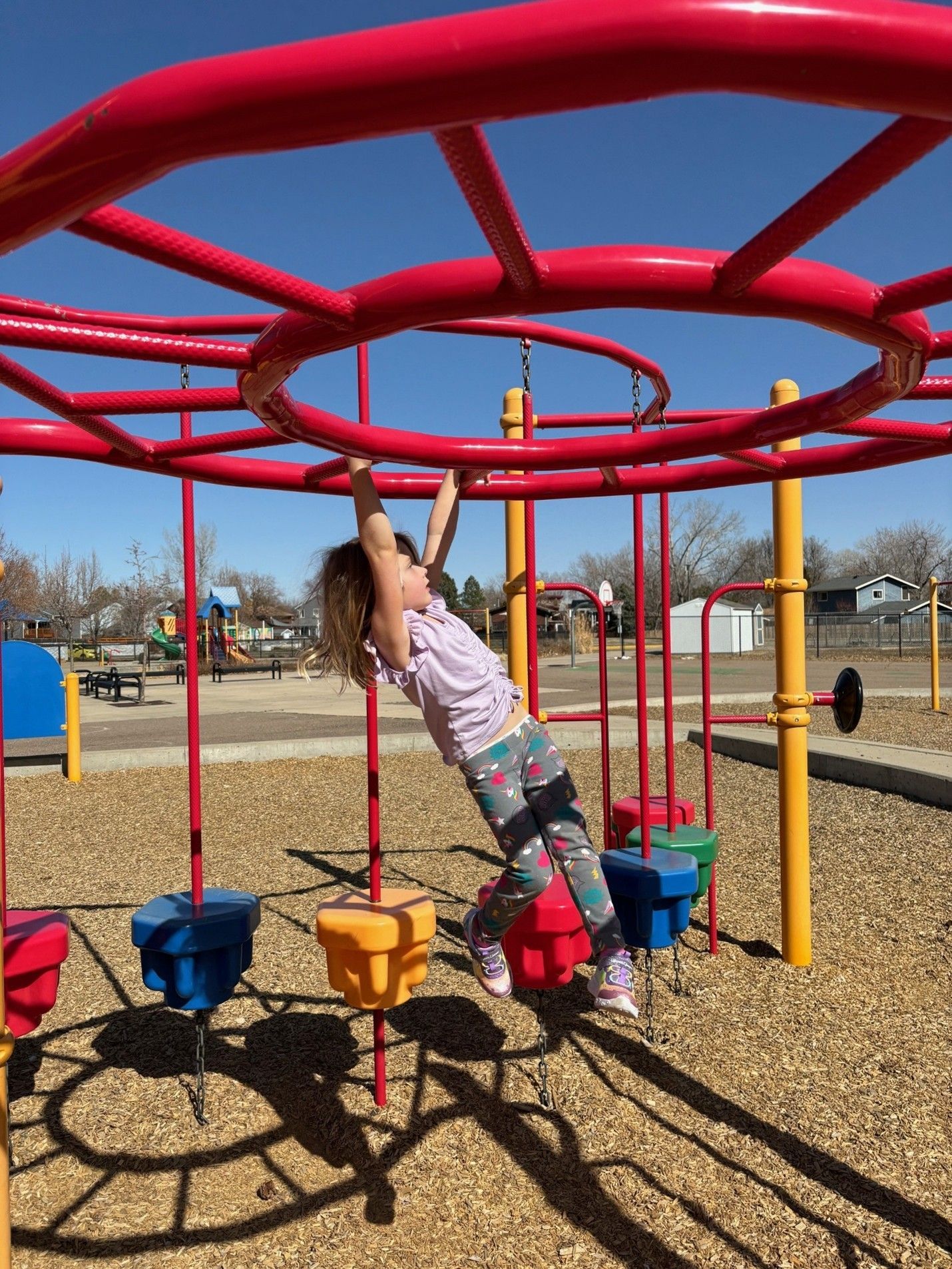 Ellie Belz on a playground outside swinging on the monkey bars