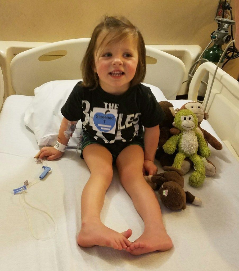 Frankie in a hospital bed smiling and surrounded by her stuffed animals