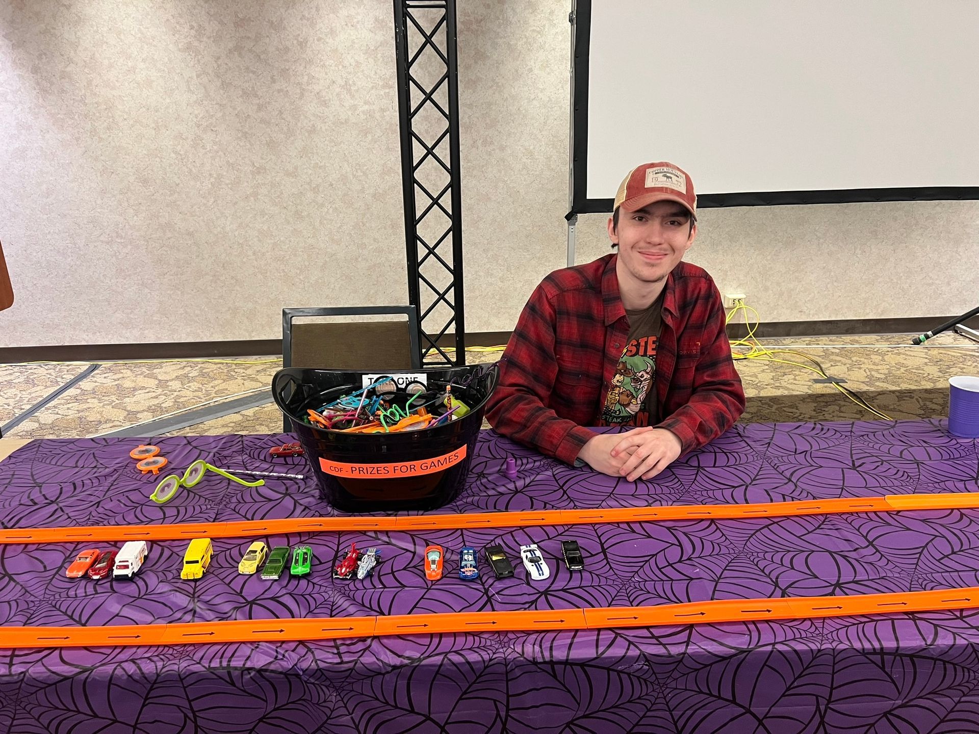 young man sitting at a table with prizes and small cars