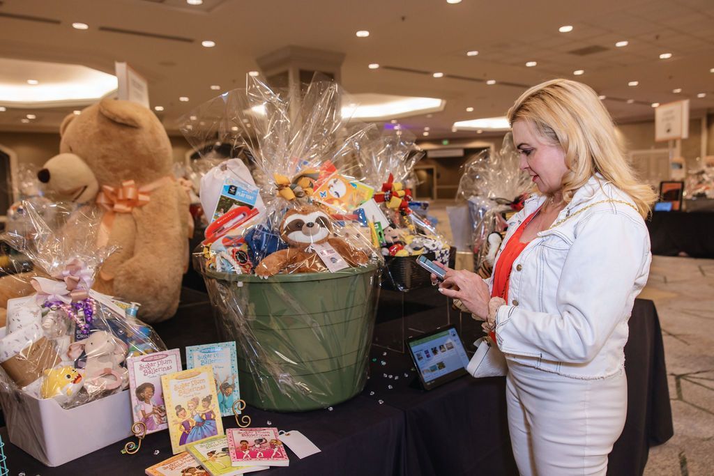 Luncheon female attendee shopping in the children's basket section of the silent auction.