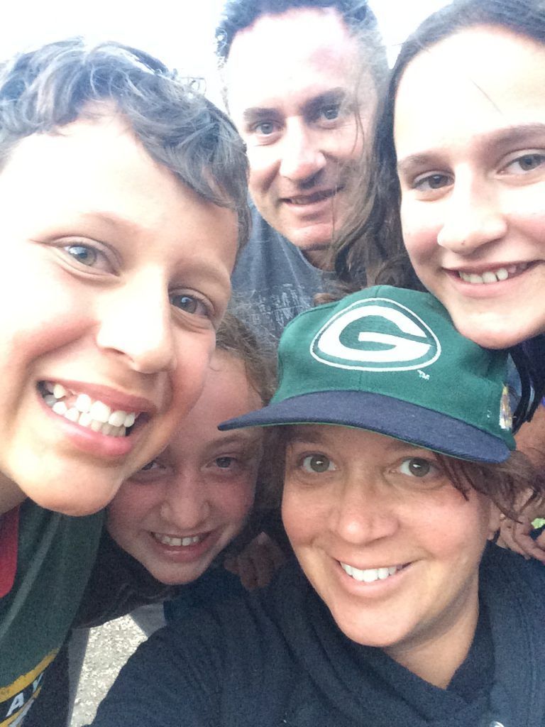 A group of people posing for a picture with one wearing a green bay packers hat