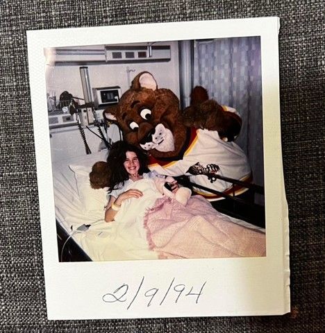 author Mary Ann Chamberlain in a hospital bed in 1994 posing with team mascot