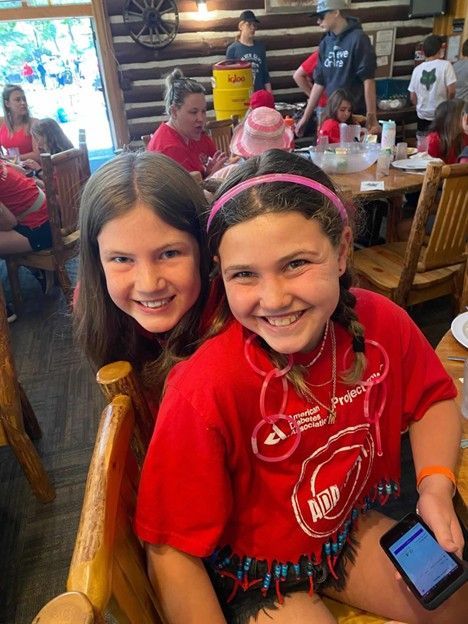 T1D camper Mia and her friend at over night camp in log lodge