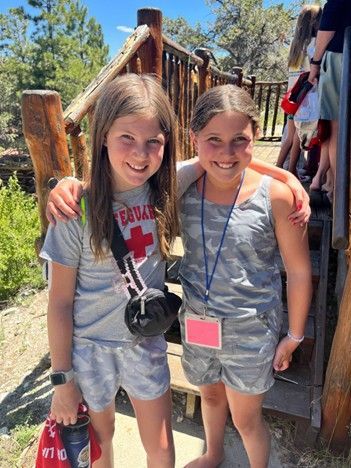 T1D camper Mia and her friend with their arms around each other and smiling
