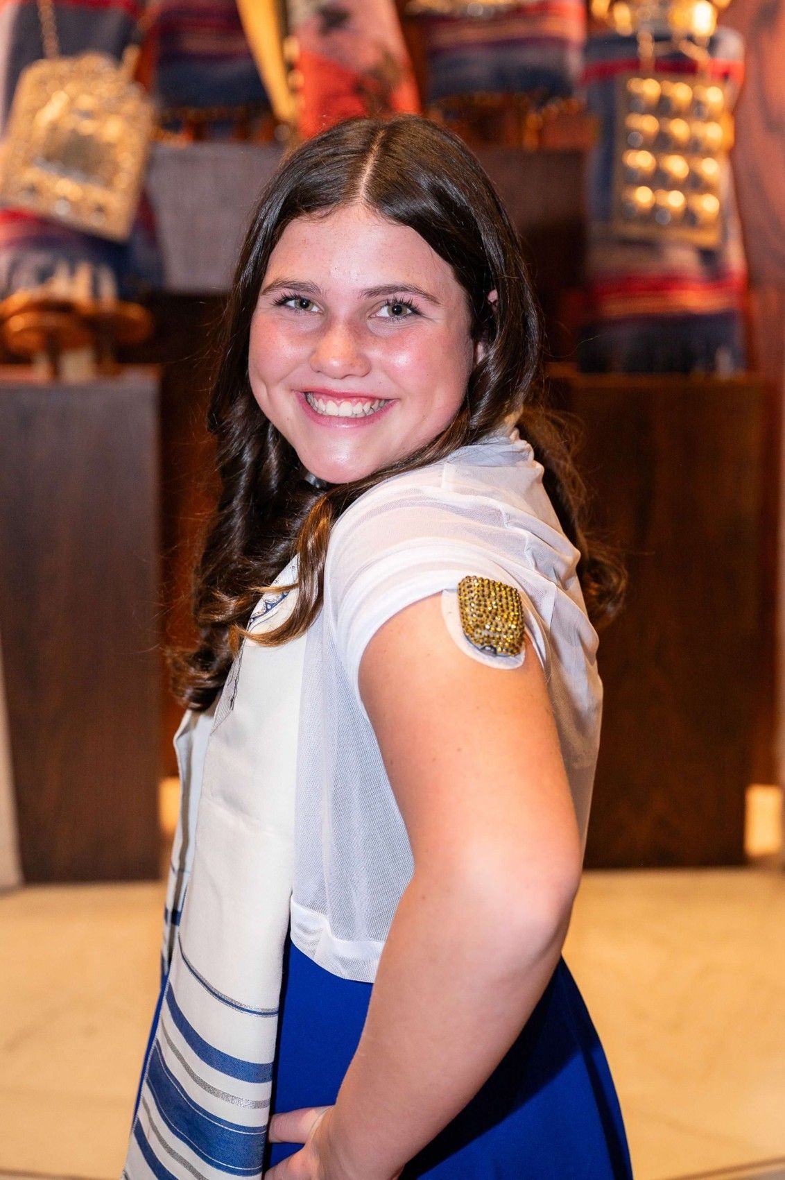 Mia with a bedazzled insulin pump on her arm and a big smile on her face