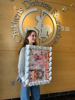 Mimi Leahy and her finished Pink Panther medical waste art project standing in front of CDF sign