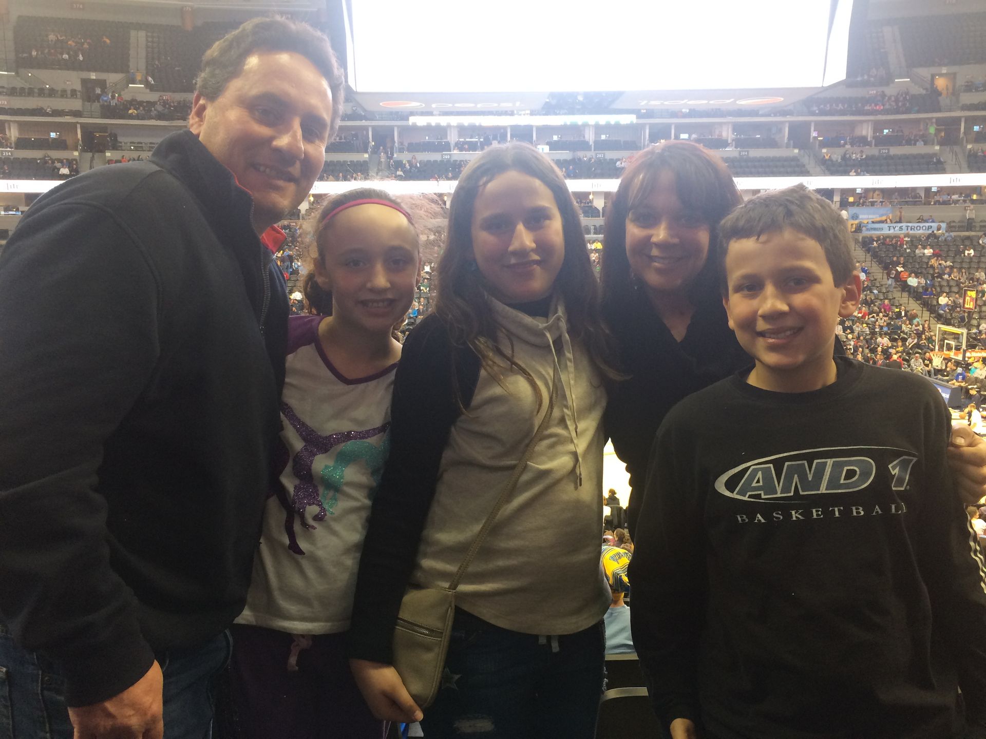 The Zarecki family posing for a picture with one wearing a green bay packers hat at a football game