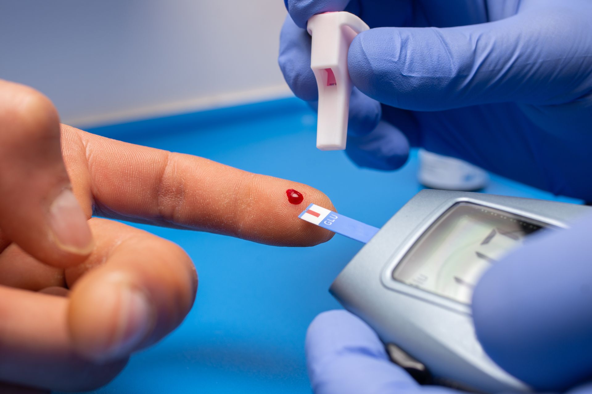 clinician checking blood from fingertip to gauge blood sugar level