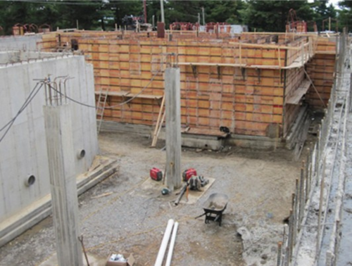 Chantier de construction avec murs en béton et coffrage en bois. Vue au niveau du sol.