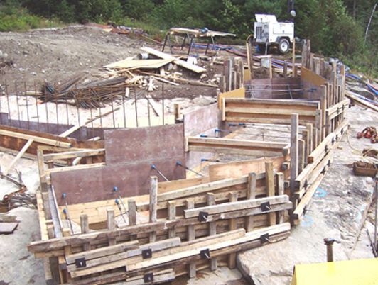 Coffrages en bois pour béton sur un chantier rocailleux.