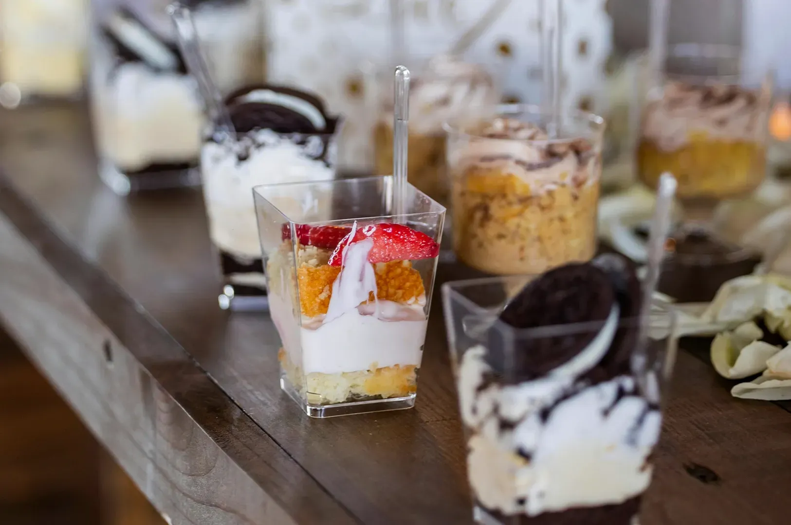 Dessert shots topped with whipped cream and fruit on a wooden table