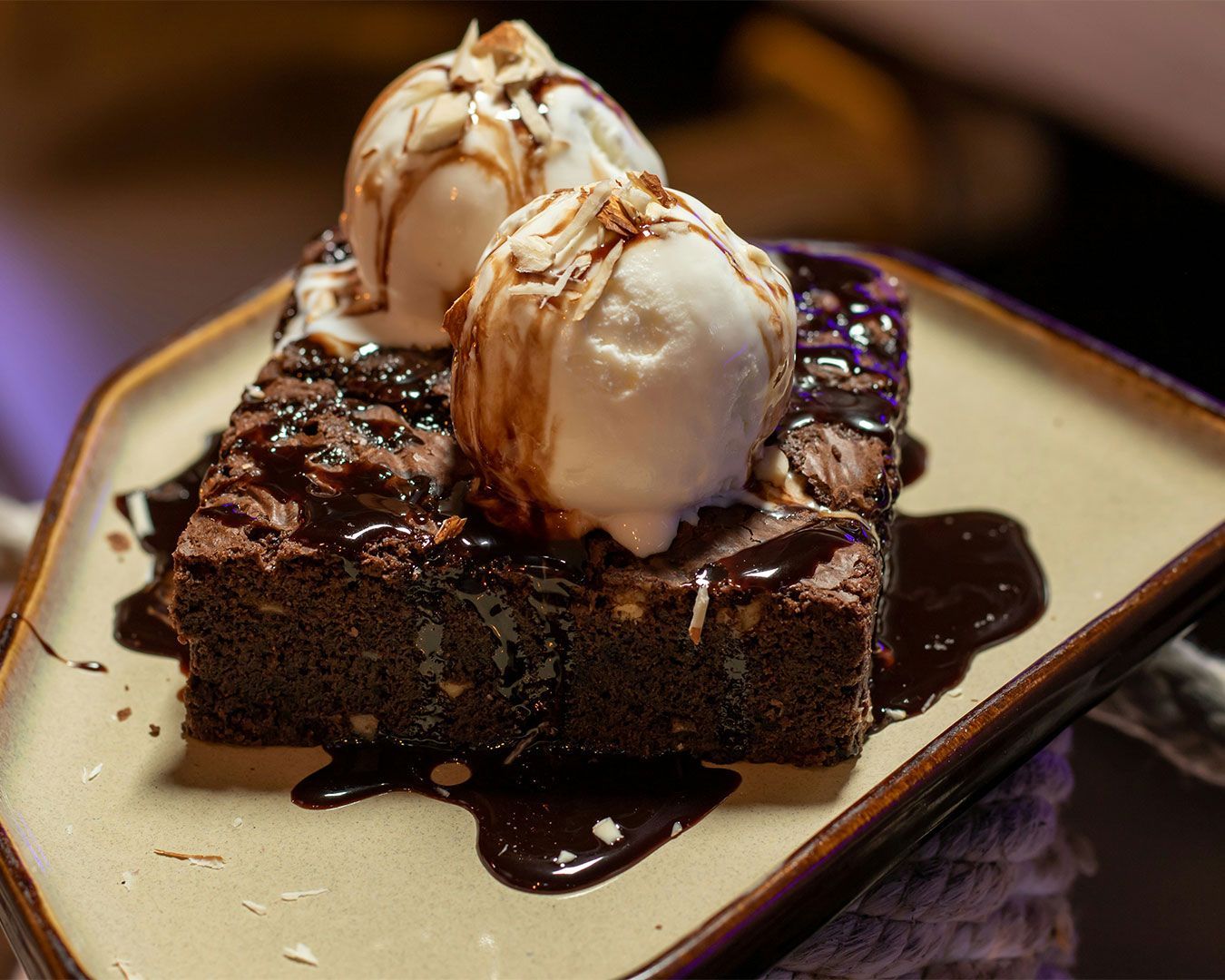 A warm, dense chocolate brownie topped with a melting scoop of vanilla ice cream, creating a rich co