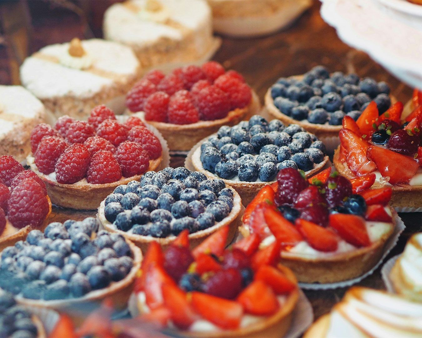 A golden-baked berries pie topped with a mix of fresh strawberries, blueberries, and raspberries, ar