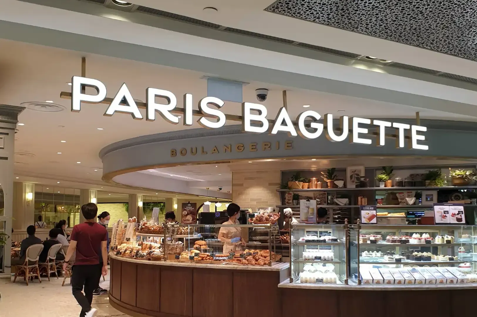Paris Baguette bakery storefront in a mall, with a lit display case and pastries inside