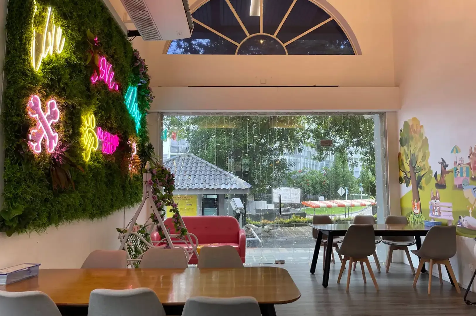 Colorful cafe interior with moss wall art, wooden tables, and large windows overlooking greenery