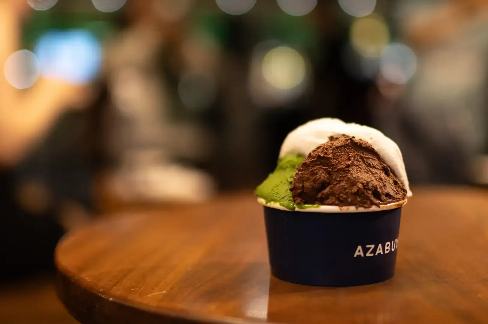 Cup of colorful gelato on a wooden table with a blurred café background