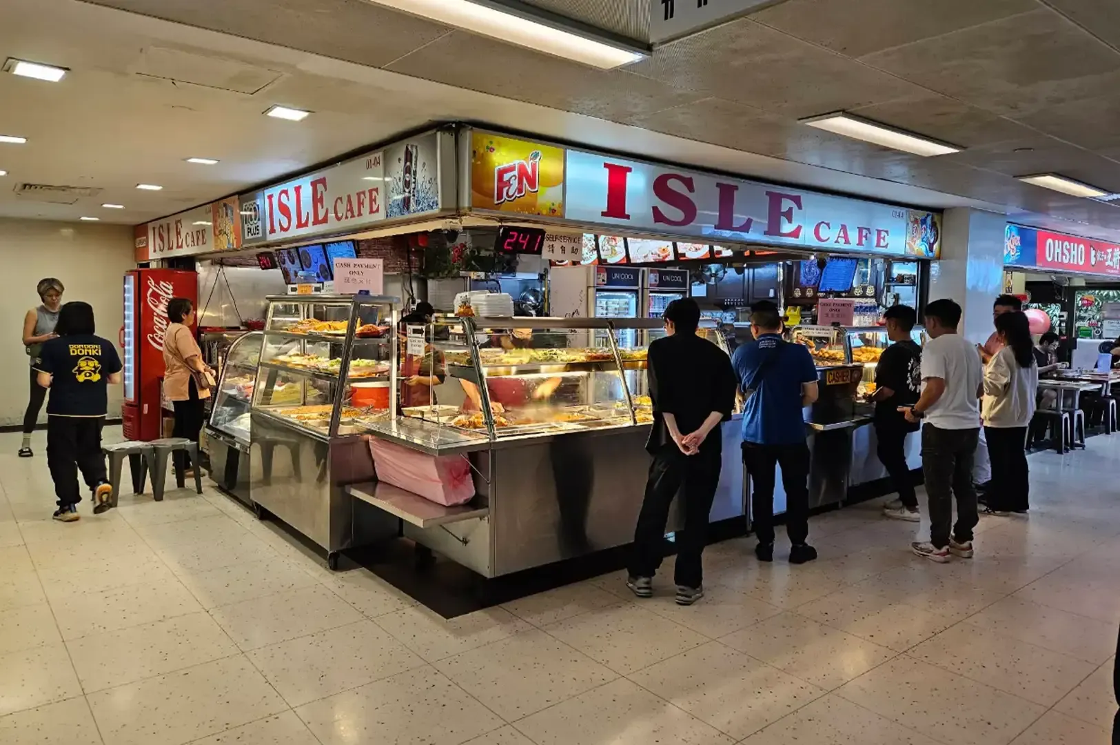 Indoor food stall labeled “ISLE,” with several customers browsing pastries and snacks.